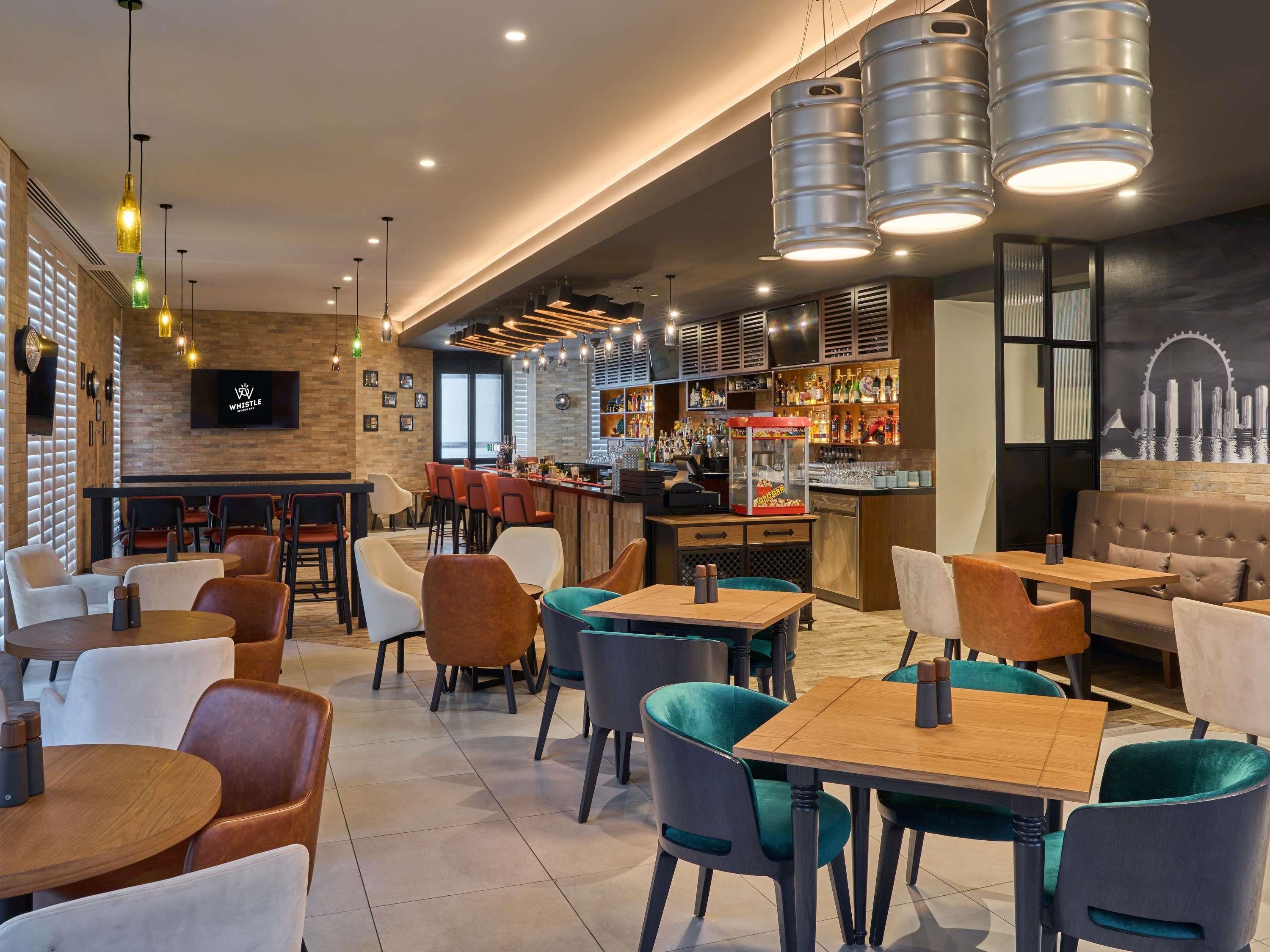A modern bar area with seating and a television screen displaying the logo 'Whistle'.