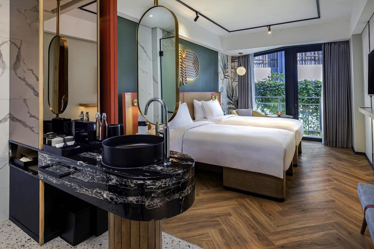 A modern hotel room with a large bed, a marble bathroom vanity, and a balcony with a view.
