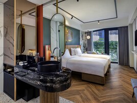 A modern hotel room with a large bed, a marble bathroom vanity, and a balcony with a view.