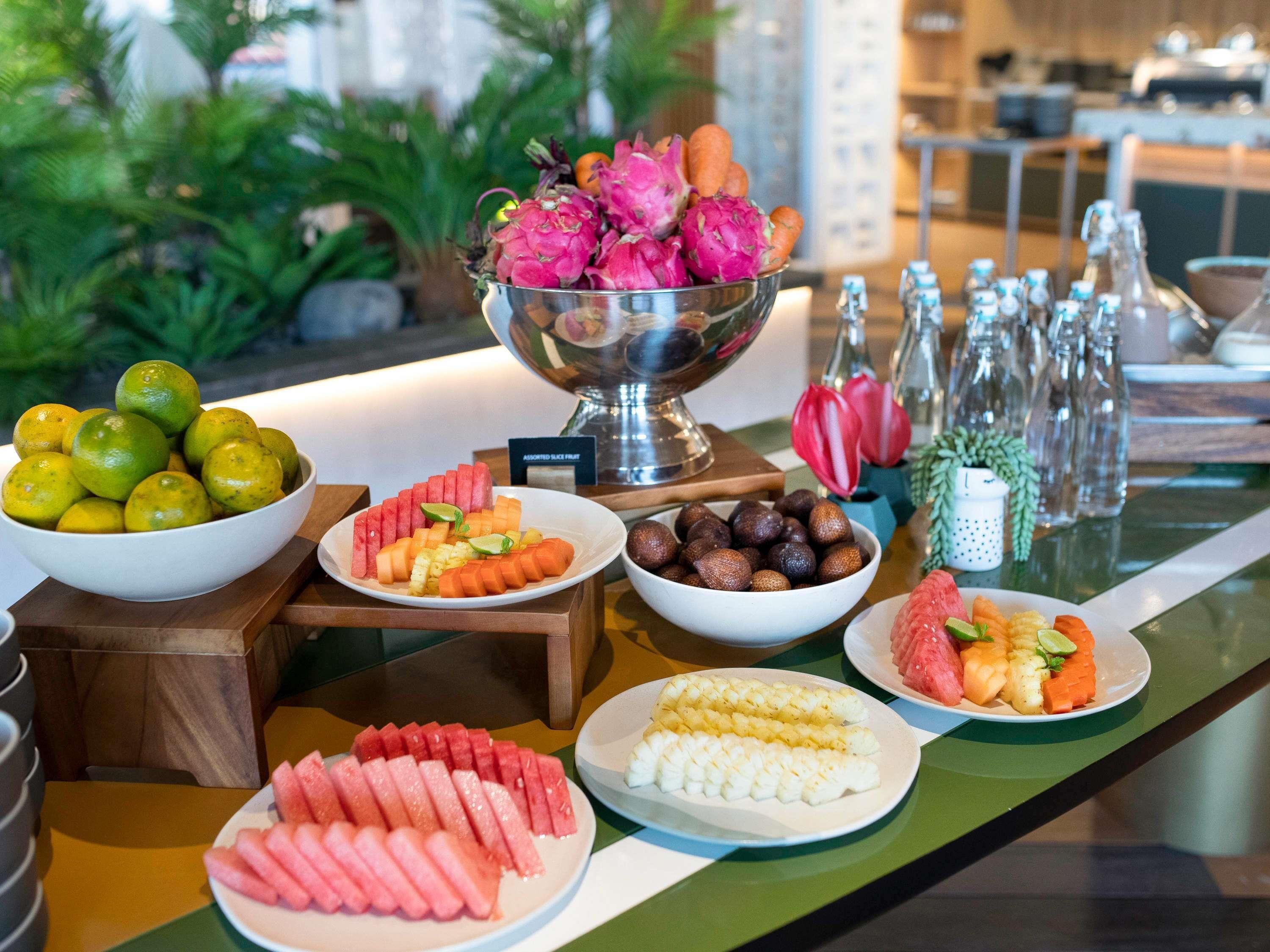 A buffet with various fruits and vegetables, including watermelon, dragon fruit, and corn.