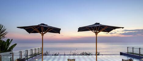 Una piscina al aire libre, sombrillas, sillones reclinables de piscina