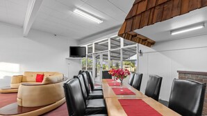 A conference room with a long table, black leather chairs, a sofa, and a TV on the wall. - Torrumbarry Motel (Torrumbarry)