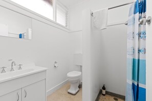 A bathroom with a white sink, toilet, and shower curtain. - Torrumbarry Motel (Torrumbarry)