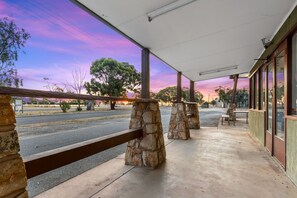 A covered outdoor area with stone pillars, a bench, and a view of the street and trees. - Torrumbarry Motel (Torrumbarry)
