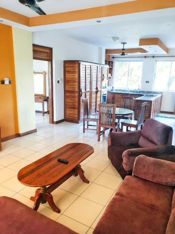 A living room with a wooden coffee table, a sofa, and a dining area with chairs and a table.