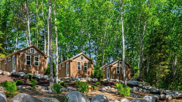 A cabin with a wooden exterior, surrounded by large rocks and trees. - Quiet Maine Cabin 2 • Hideaway in the Trees • Sauna (Stockton Springs)