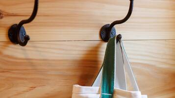 A wooden floor with two metal hooks and a white bag with green accents hanging from one of the hooks.