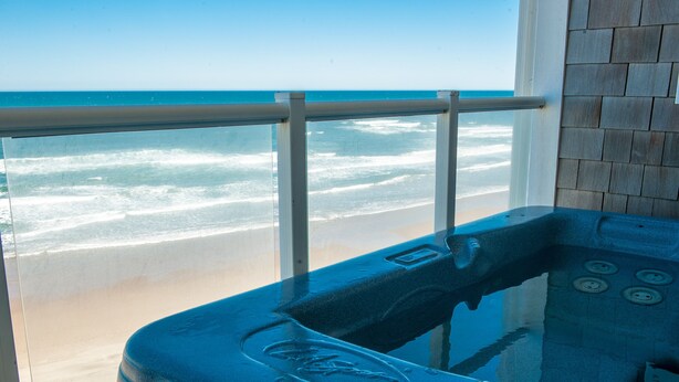 Un baño con bañera, vistas a la playa y pared de azulejos.