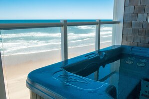 Un baño con bañera, vistas a la playa y pared de azulejos.