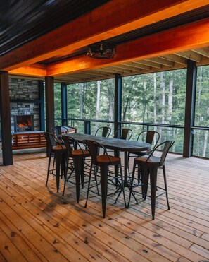 Une terrasse en bois avec une cheminée en pierre et une table entourée de chaises.