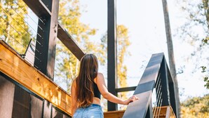 A person descending a wooden staircase with metal railings, surrounded by trees. - I'll Have S'More - Hocking Hills -Lux In & Out (Hocking Hills)