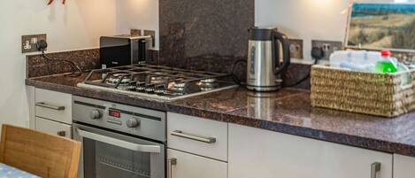 A modern kitchen with a gas stove, oven, and a coffee maker.