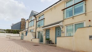 A row of townhouses with a paved driveway, large windows, and a flat roof. - Constantine Bay Cottage (Padstow)