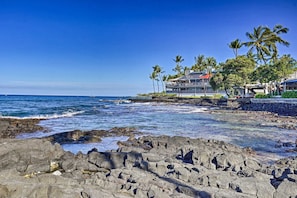 A coastal hotel with a rocky shoreline, palm trees, and ocean views. - Outstanding Oceanfront Studio - Kona Islander Inn Condos Condo by RedAwning (Kailua-Kona)