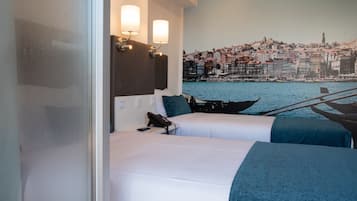 Een hotelkamer met twee bedden, uitzicht op een kustplaats en een aan de muur bevestigd telefoon.