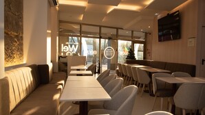 A modern restaurant interior with a long counter, cushioned seating, and a large window. - Hotel Porto Interface Trindade By Kavia (Porto)