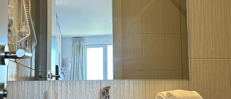 A modern bathroom with a large mirror, a sink, and a shower.