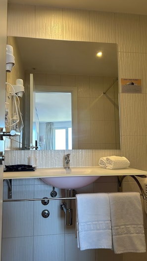 Un baño moderno con un espejo grande, un lavabo y una ducha.