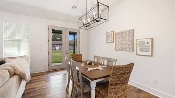 Un coin repas avec une table en bois, des chaises en osier et un lustre.