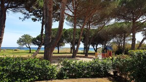 A park with trees, a playground, and a view of the sea. - At the end of the garden, the pine forest and the beach (Poggio-Mezzana)