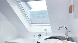 A modern bathroom with a skylight, a bathtub, a sink, and a towel rack.