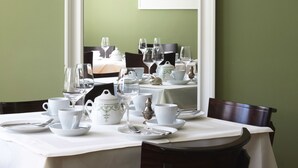 A dining table set with white tableware and a framed picture on the wall.