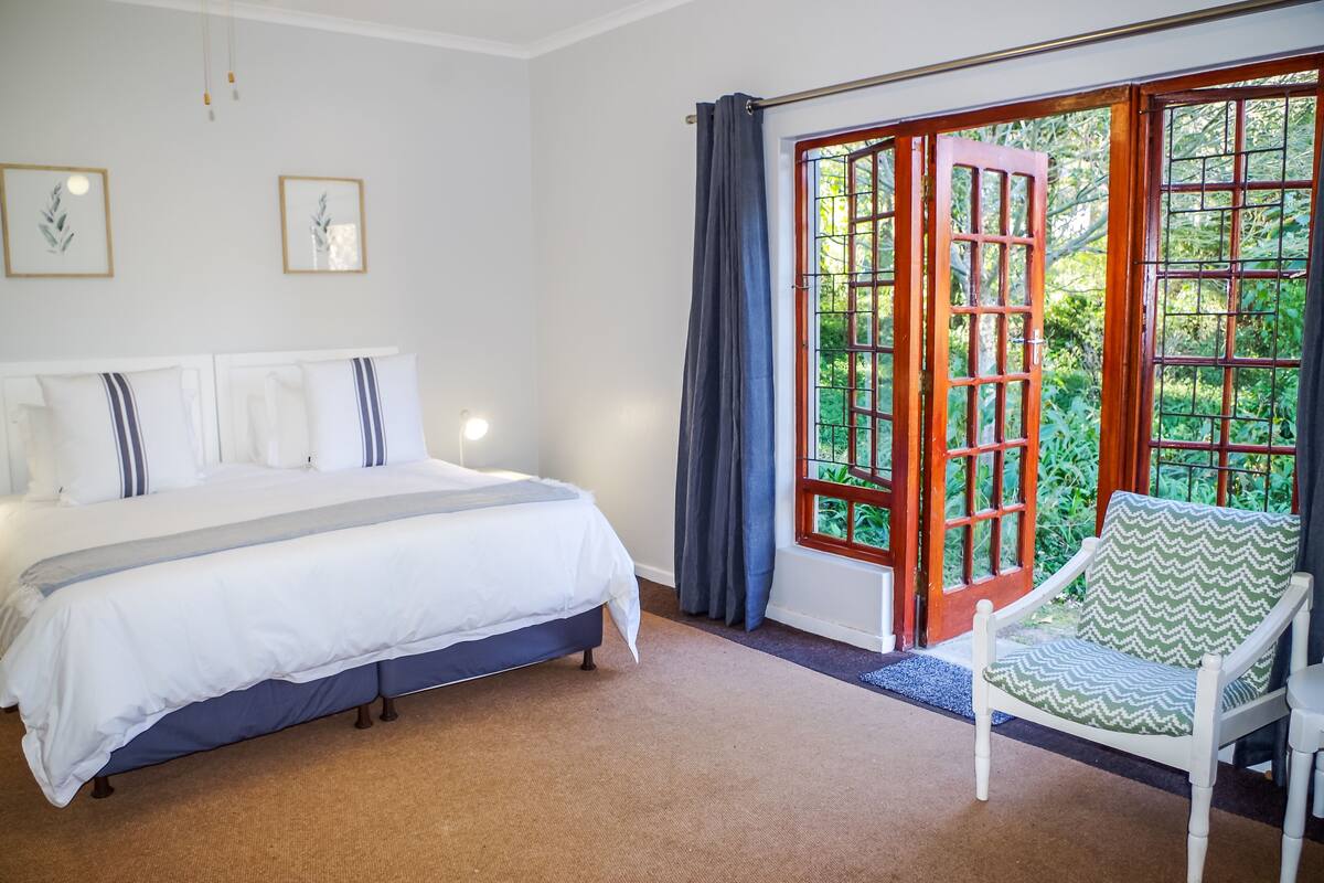 Une chambre à coucher avec un lit, une chaise et une grande fenêtre donnant sur un paysage verdoyant.