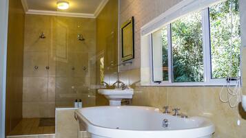 Een moderne badkamer met een inloopdouche, een vrijstaand bad en een groot raam dat voor natuurlijk licht zorgt.