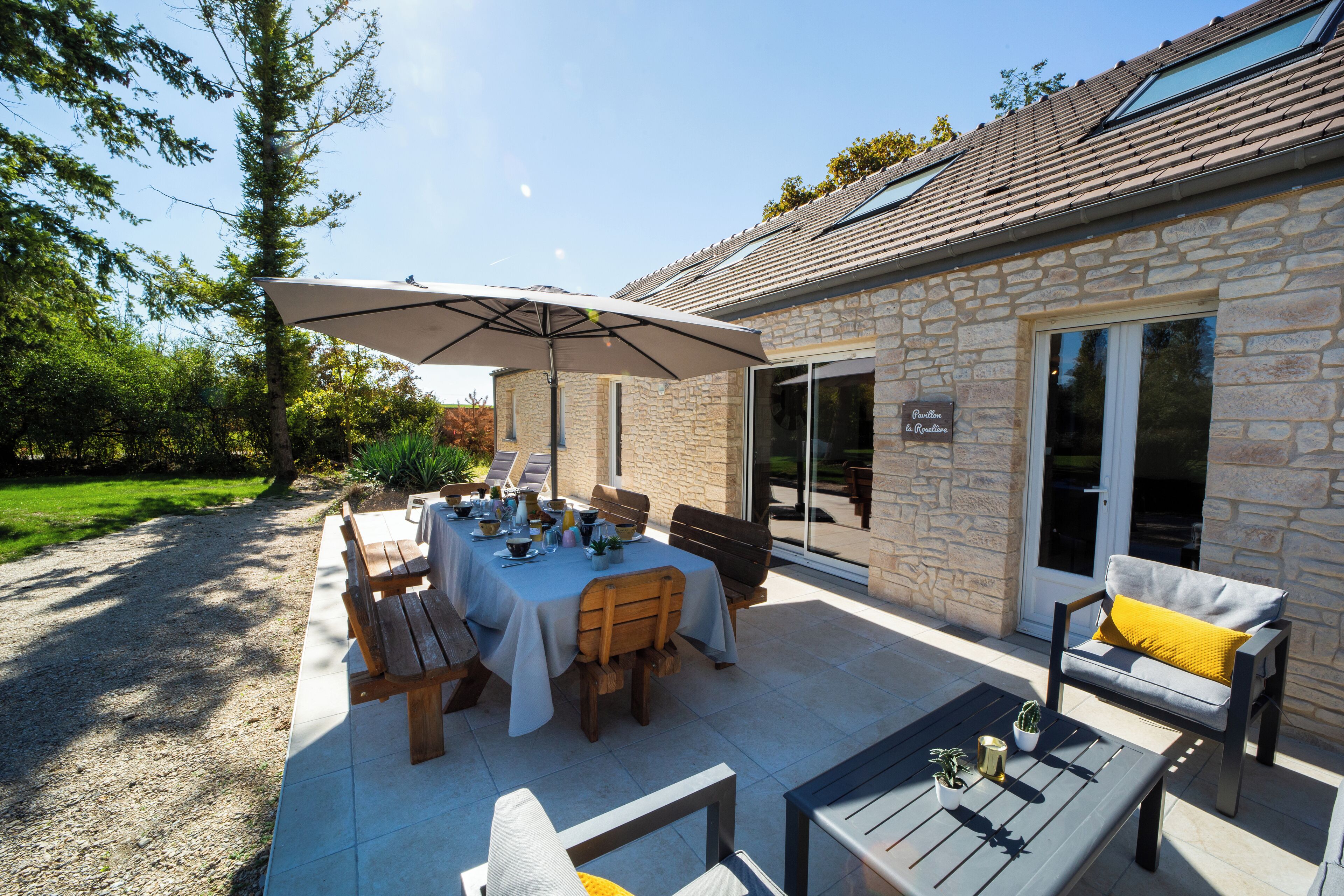 Un patio al aire libre con una mesa de comedor, sillas y una sombrilla.
