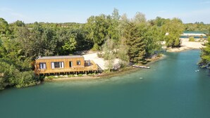 Una cabaña de madera junto a un río, rodeada de árboles.