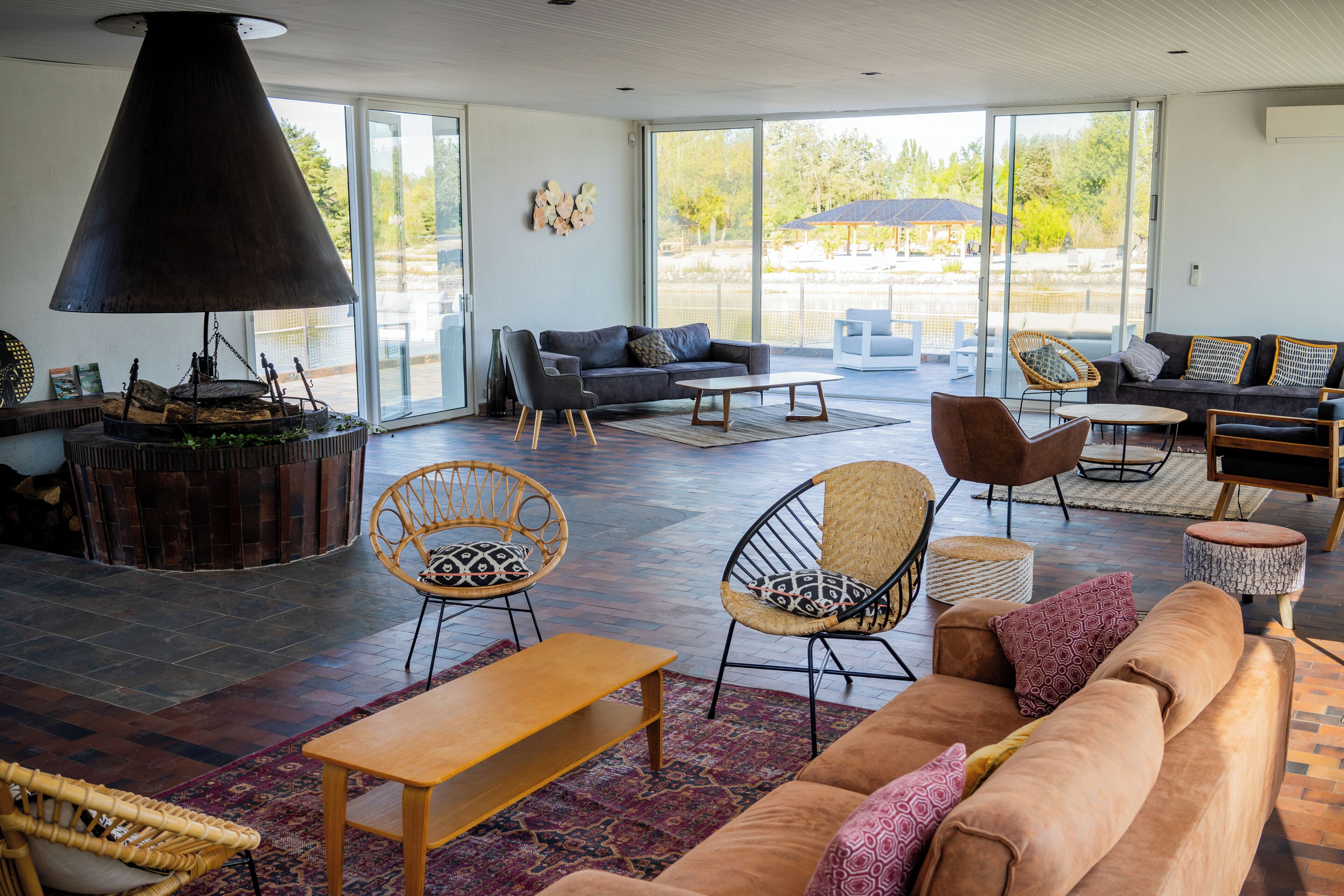 A spacious living area with a large black lamp, comfortable seating, and a view through large glass doors.