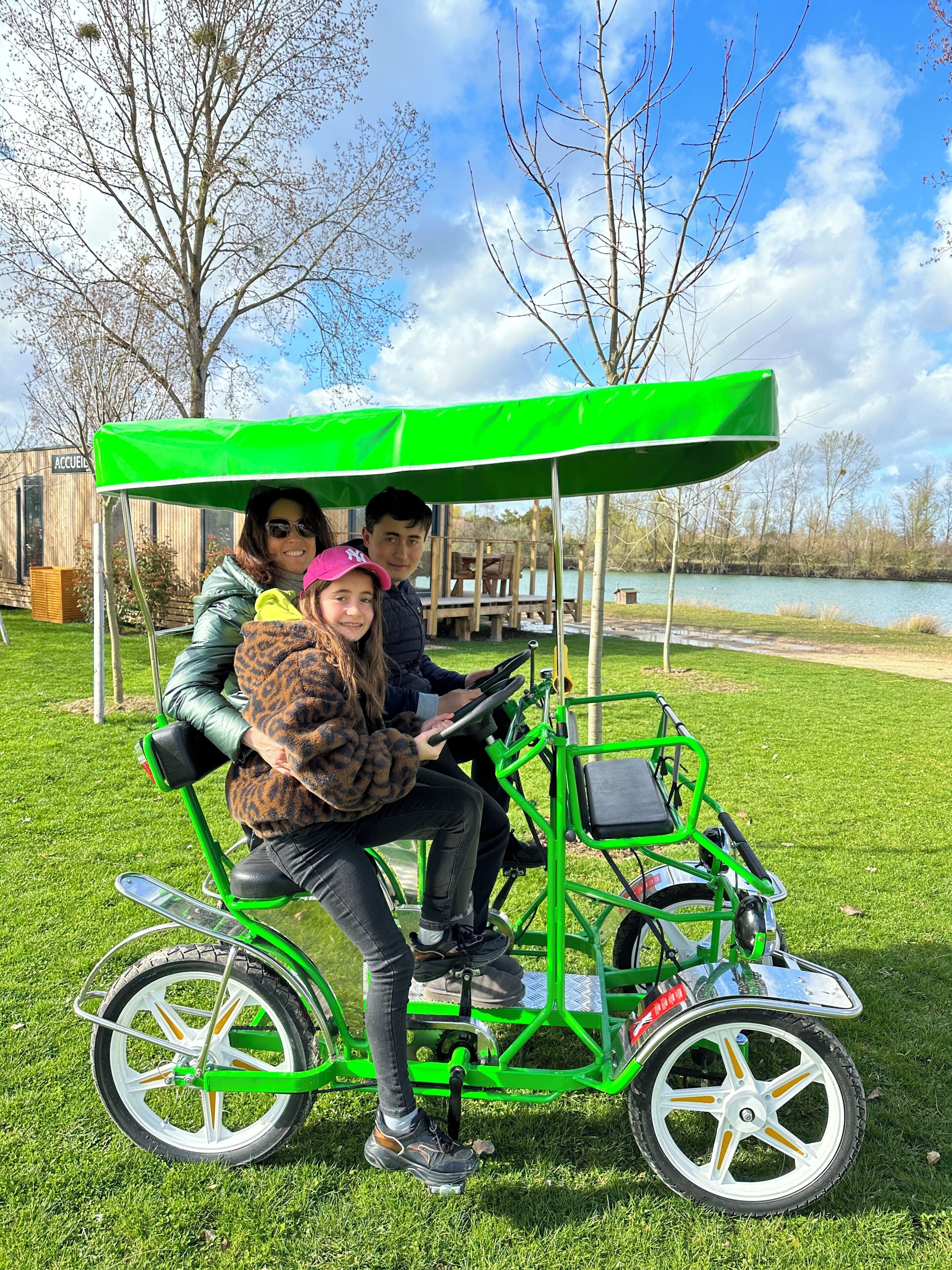 Un carrito de golf verde con toldo, estacionado sobre césped cerca de un cuerpo de agua.
