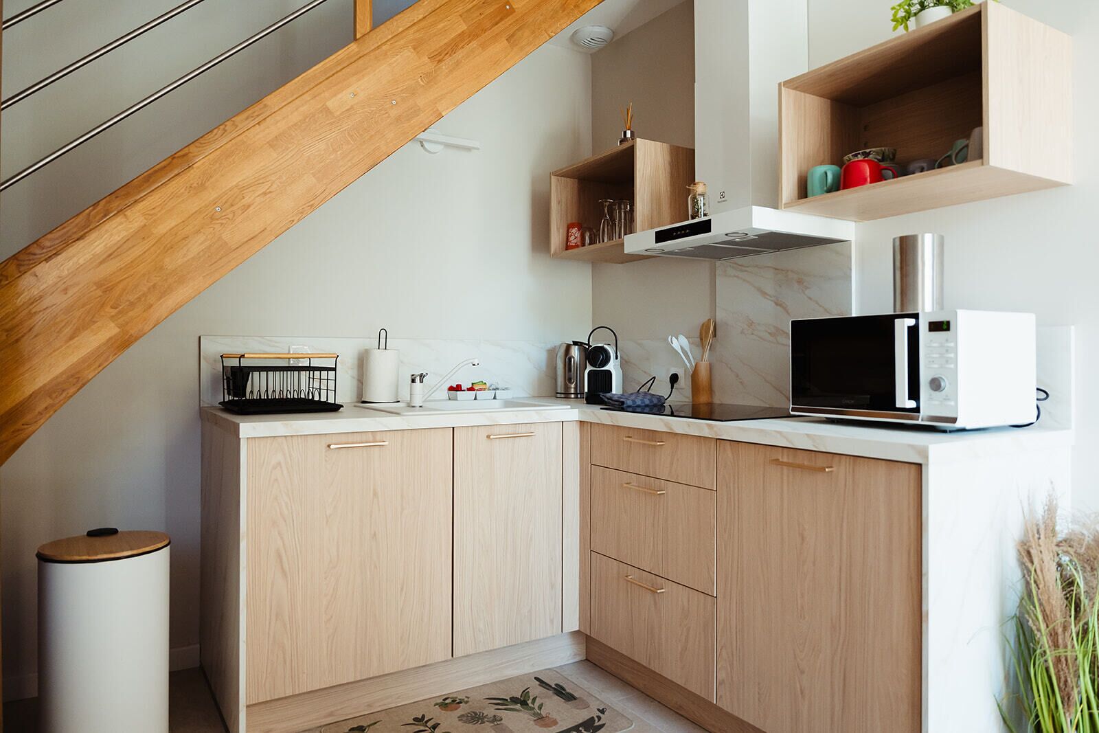 Una cocina compacta con gabinetes de madera, un microondas y un lavamanos.