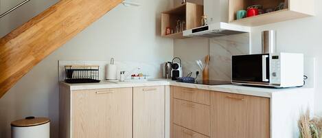 Una cocina compacta con gabinetes de madera, un microondas y un lavamanos.