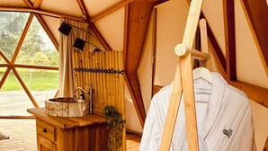 Un interior de madera con un banco, un lavamanos y una bata colgada.