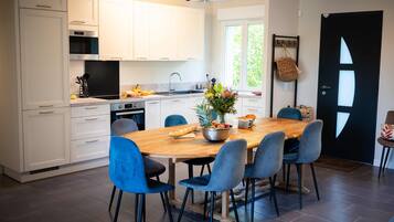A modern kitchen with white cabinets, a wooden dining table, and blue chairs.