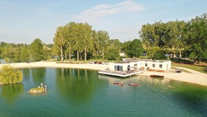 Propiedad frente al lago con muelle, un bote y un edificio con terraza.
