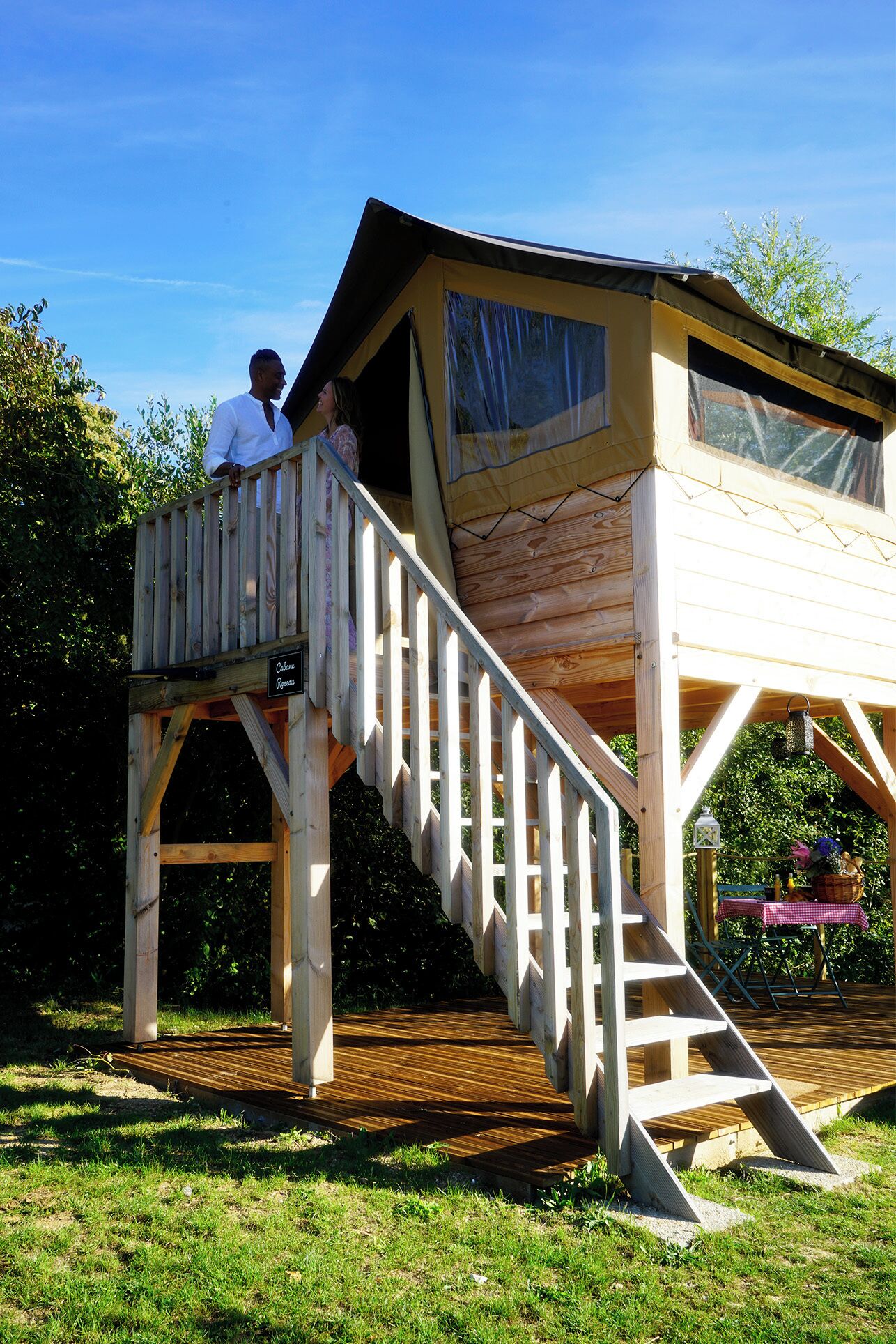 A wooden playhouse with a ramp and a small porch.