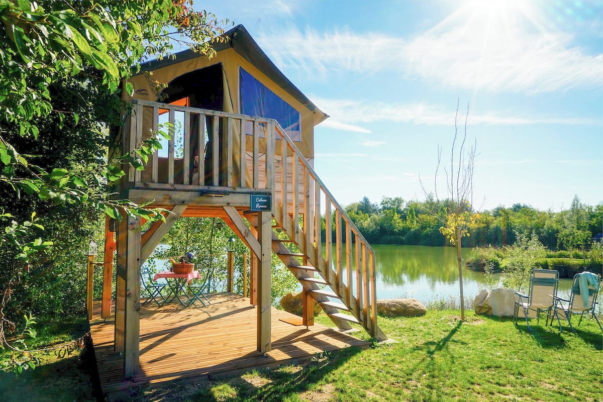 Una terraza de madera con una escalera que lleva a una casa en los árboles.