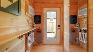 Un estrecho pasillo de madera con una puerta al final, que conduce a un espacio exterior.