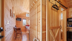 Un interior de madera con comedor, un escoba y un perchero.