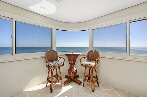 Enjoy breathtaking ocean views from this corner room, featuring two comfortable chairs and a small table.