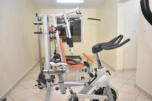 A gym with exercise equipment, including a bench press, a squat rack, and a stationary bike.