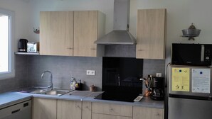Eine moderne Küche mit Edelstahlgeräten, Holzschränken und einem integrierten Geschirrspüler.