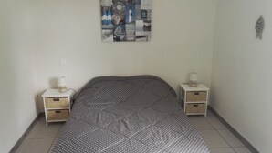 Ein Schlafzimmer mit einem Bett, zwei Nachttischen mit Lampen, einer Wanduhr und einer gerahmten Collage an der Wand.