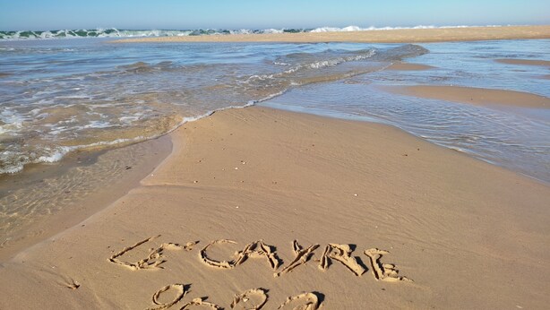 Ein Strand mit den Schriftzügen "LE CAYRE 2022" im Sand.