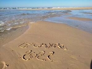 A sandy beach with the words 'LE CAYRE 2022' written in the sand.