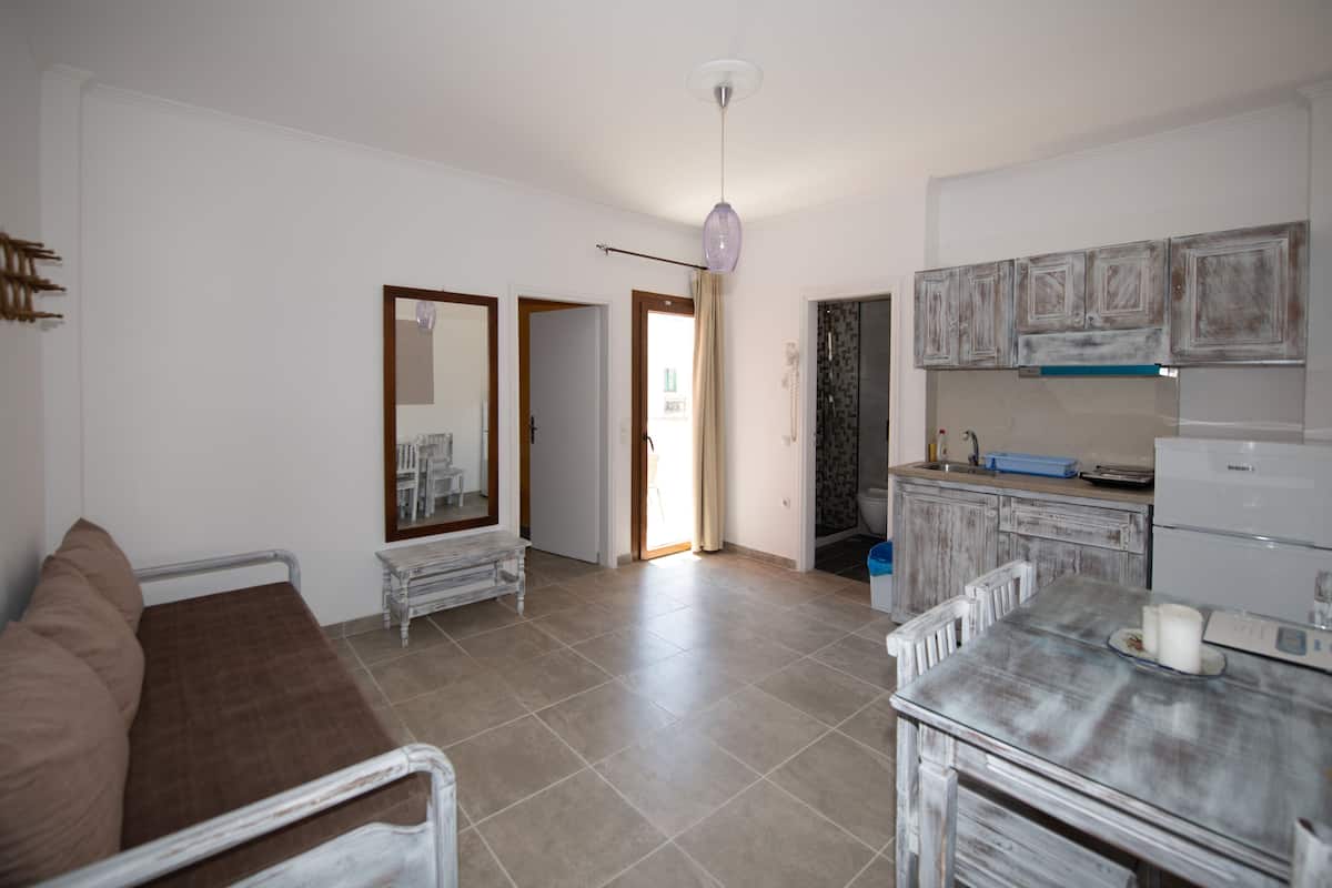 Una sala de estar con sofá, una mesa de comedor y una cocina con armarios y un refrigerador.