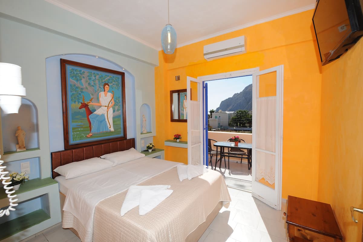 Un cuarto de hotel con cama, un cuadro, balcón y vistas a la montaña.
