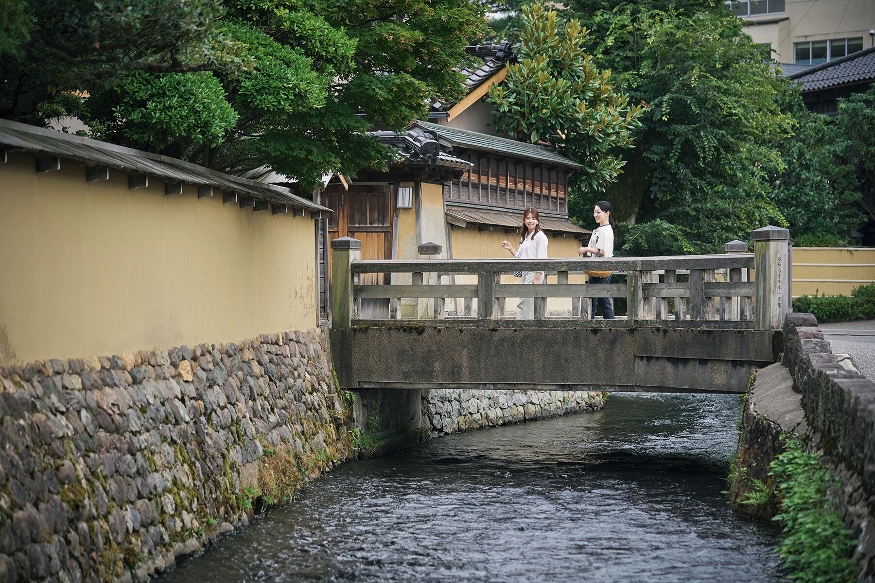 Eine Stegenbrücke über einen schmalen Wasserlauf, gesäumt von traditionellen Gebäuden.